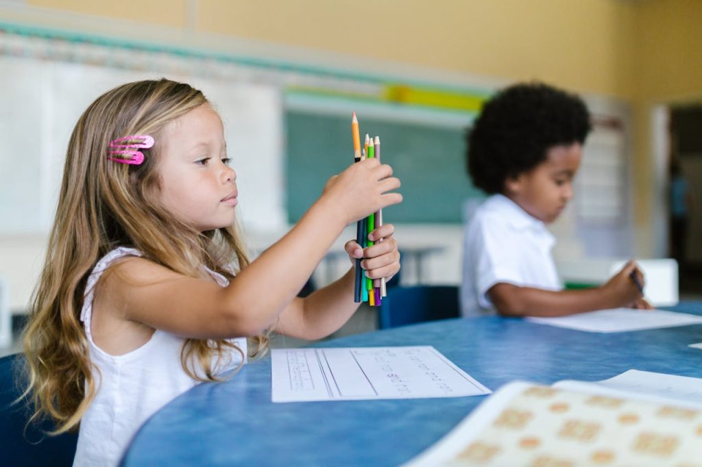 Two children focused on classroom learning with colored pencils and paper.